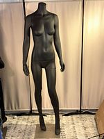 Front view of black female mannequin standing on metal base with foldable arms and legs in neutral position.