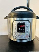 Front view of Instant Pot Duo 7-in-1 electric pressure cooker showing digital display with error code E1 and control buttons.
