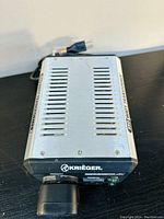 Top view of silver metal voltage transformer with cooling vents, power cord with US plug attached. Krieger logo visible on the front.