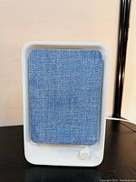 Front view of Levoit air purifier showing blue fabric front panel and white knob.