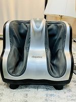 Front view of OSIM iSqueeze calf and foot massager showing two padded foot/calf slots and silver-black casing.