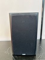 Black B&W speaker front covered with black fabric grille with B&W logo at bottom center.