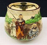 Front and side view of the ceramic jar showing monks fishing motif and lid on top.