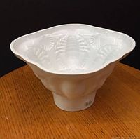 Side view of white ironstone china jelly mould showing embossed lobsters and seashells and the overall shape.
