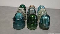 Front view showing all nine Hemingray glass insulators in various colors, some with visible wear.