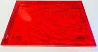 Top view of red acrylic serving tray showing rectangular shape, glossy finish, and wave texture
