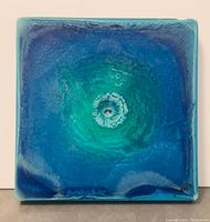 Front view of the acrylic wall art showing the vibrant blue and green concentric circles with textured glossy finish and signed in corner.