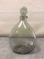 Front view of the Holmegaard clear glass decanter with stopper in place, showing rounded body and neck.