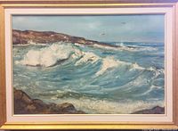 Framed ocean scape painting showing crashing waves, rocky shore, and distant horizon.
