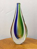 Front view of the Murano Poli cased glass vase showing the teardrop shape with blue and green colored inner bands and amber highlights inside clear glass casing.