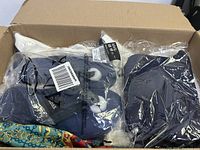 Top view of large box showing packaged navy blue winter gloves with labels and barcodes visible.