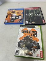 Overview photo showing three game cases: NHL 19 for PS4, Enter the Matrix for PS2 Greatest Hits, Marc Ecko's Getting Up for Xbox