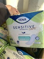 Close-up of one pack of Tena Sensitive Care pads showing brand, series, and absorption level.