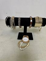 Full lot of women's bracelets displayed on black velvet T-bar. Various styles including rhinestone bangles, cuff, gemstone, and beaded bracelets.