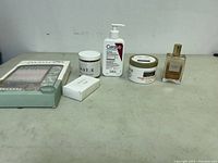 Overview of skincare items, cream jars, lotion, boxed cosmetic, and fragrance bottle arranged on a plain surface.