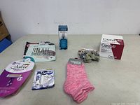 Lot overview with displayed items on table: pink socks, lip care products, snail sheet mask, hair scrunchies in box, blue nail tool, and box of CeraVe lotions