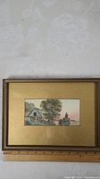Photo showing the full framed watercolour painting with a farmhouse and trees in a gold textured mat and frame.