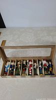 Photo showing the full set of 9 nutcracker ornaments in a divided box with plastic window lid.