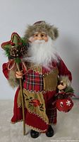 Full view of 16 inch tall Christmas Santa figurine holding star staff and red bag