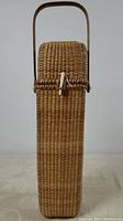 Front view of rectangular Nantucket-style wicker wine carrier with toggle closure and upright handle.