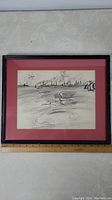 Framed black and white print of a harbour scene with boats and birds, with red mat and black frame.