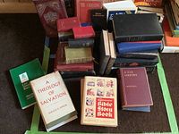 Photo showing a spread of religious books including Bibles and study references, with titles such as 'A Theology of Salvation' and 'Government Bible Store Book' clearly visible among other assorted books.