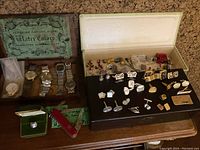Wooden jewelry box lid displaying assorted cufflinks