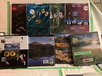 Eight sealed souvenir booklets of Canadian postage stamps arranged on a table showing various cover designs and price stickers.