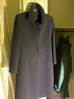 Navy wool fall jacket hung on white door