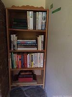 Books arranged on a four-shelf bookcase, close view showing spines of various books stacked vertically and horizontally.
