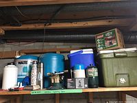 Shelves holding the camping gear items including water containers, thermoses, not fully loaded but showing all pieces