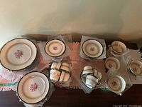 Wide overhead view of all dinner plates, side plates, dessert plates, teacups, and saucers in protective wrap.