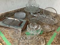 Overview of all glassware and serving dishes including various bowls, plates, and hot plate on kitchen counter