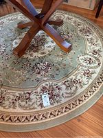 Full top-down view of round area rug underneath table base showing floral pattern and colors.
