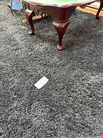 Gray shag area rug under a wooden table showing texture and size.