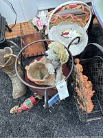 Photo showing dog-shaped planter on metal stand, brown woven basket, white basket with floral cloth, wire decorative rack, cowboy boot-shaped planter, and colorful horse figurine on carpet.