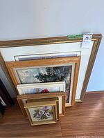 Six framed art pieces stacked visible, showing variety in size and frame styles