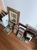 Wide view of 24 assorted frames arranged on the floor, showing variety in size, material, and styles