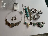 Overview of the entire jewellery lot showing all items including bracelets, rings, earrings, and necklace with turquoise accents.