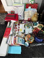 Overview photo showing an assortment of holiday-themed items including Christmas tree box, linens, gift bags, and Halloween decor.
