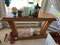 Oak sofa table with various items on top and underneath, measuring tape and size label visible.