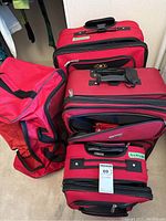 Four red soft-sided suitcases grouped together, showing the different styles and sizes.
