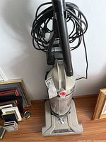 Full view of Hoover WindTunnel vacuum showing upright position, hose attached and coiled power cord.