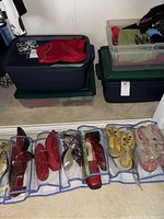 Wide view of 4 storage bins with women's clothing and 7 pairs of shoes in a hanging organizer including red, yellow and pink sandals