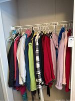 Full view of women's coats and scarves hanging on a rack; multiple colors and sizes represented