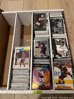 Overhead photo of a white box with dividers containing stacks of hockey cards including vintage and recent hits and inserts