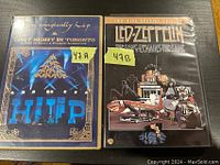 Photo showing the two concert DVDs side by side. The Tragically Hip DVD titled 'That Night in Toronto' on the left with a blue stage image. The Led Zeppelin DVD titled 'The Song Remains the Same' on the right with an illustrated cover.