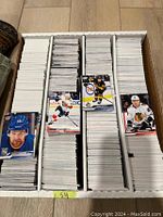 Overhead photo showing densely packed divided box with approximately 3200 hockey base cards with visible front cards featuring NHL players.