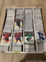 Top down photo of four rows of hockey trading cards packed tightly in a divided box showing various player images from NHL teams such as Calgary Flames, Colorado Avalanche, Dallas Stars, and Winnipeg Jets.