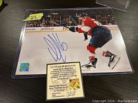 Signed 8x10 photo of Aleksander Barkov in Panthers uniform, with his autograph and the Certificate of Authenticity visible underneath in protective clasped sleeve.